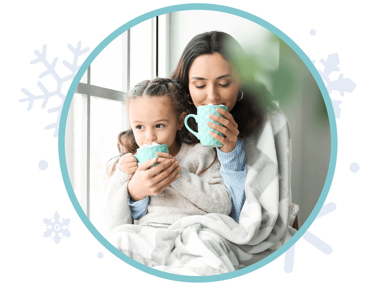 mother and daughter sipping hot chocolate in front of a window while wrapped in a blanket